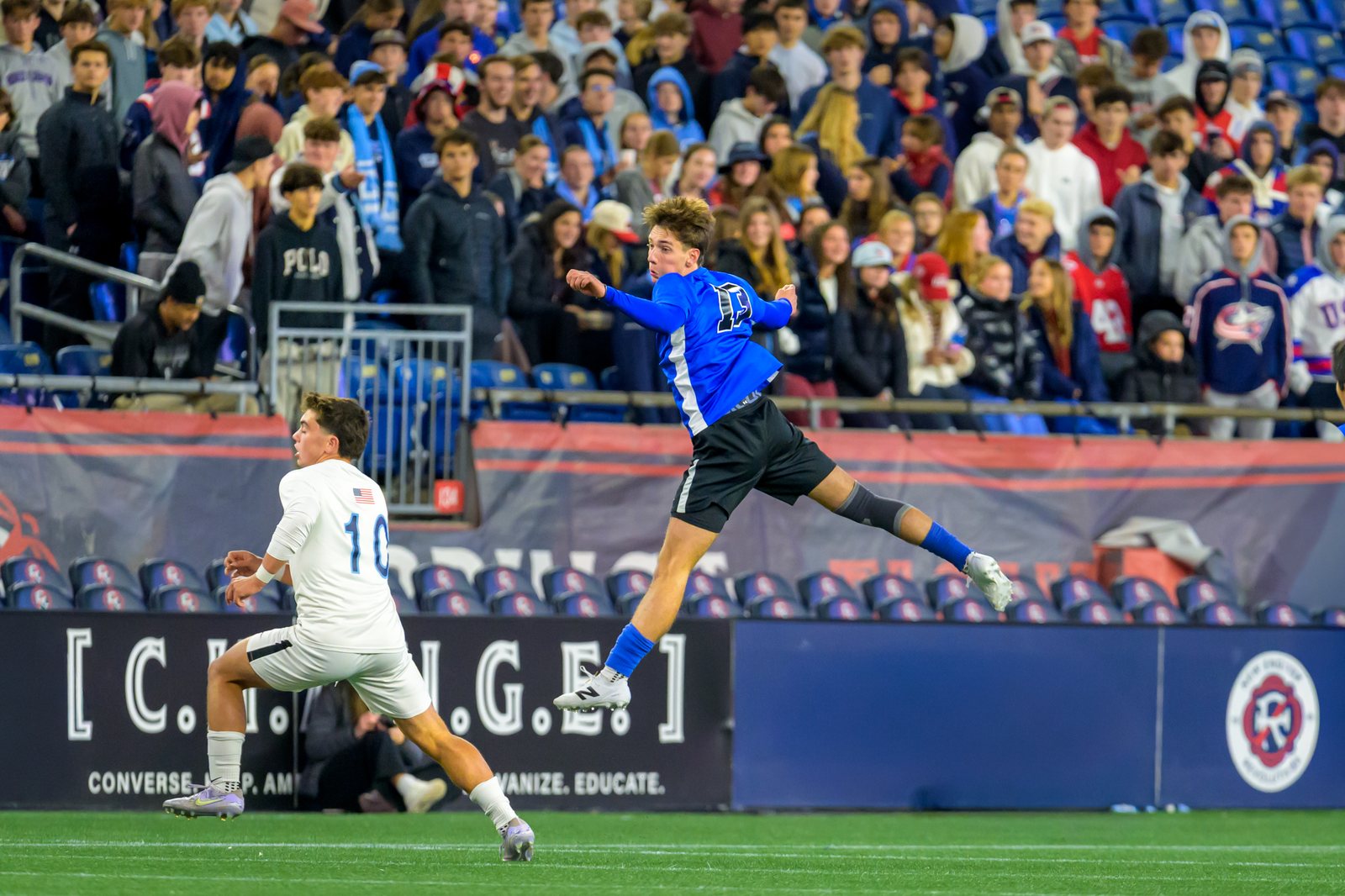 A soccer player airborne in front of the student section